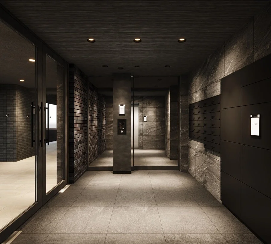 集合住宅のモダンでスタイリッシュなエントランスホール。石材の壁と落ち着いた照明が特徴で、メールボックスやインターホンが設置されており、洗練された空間を演出しています。