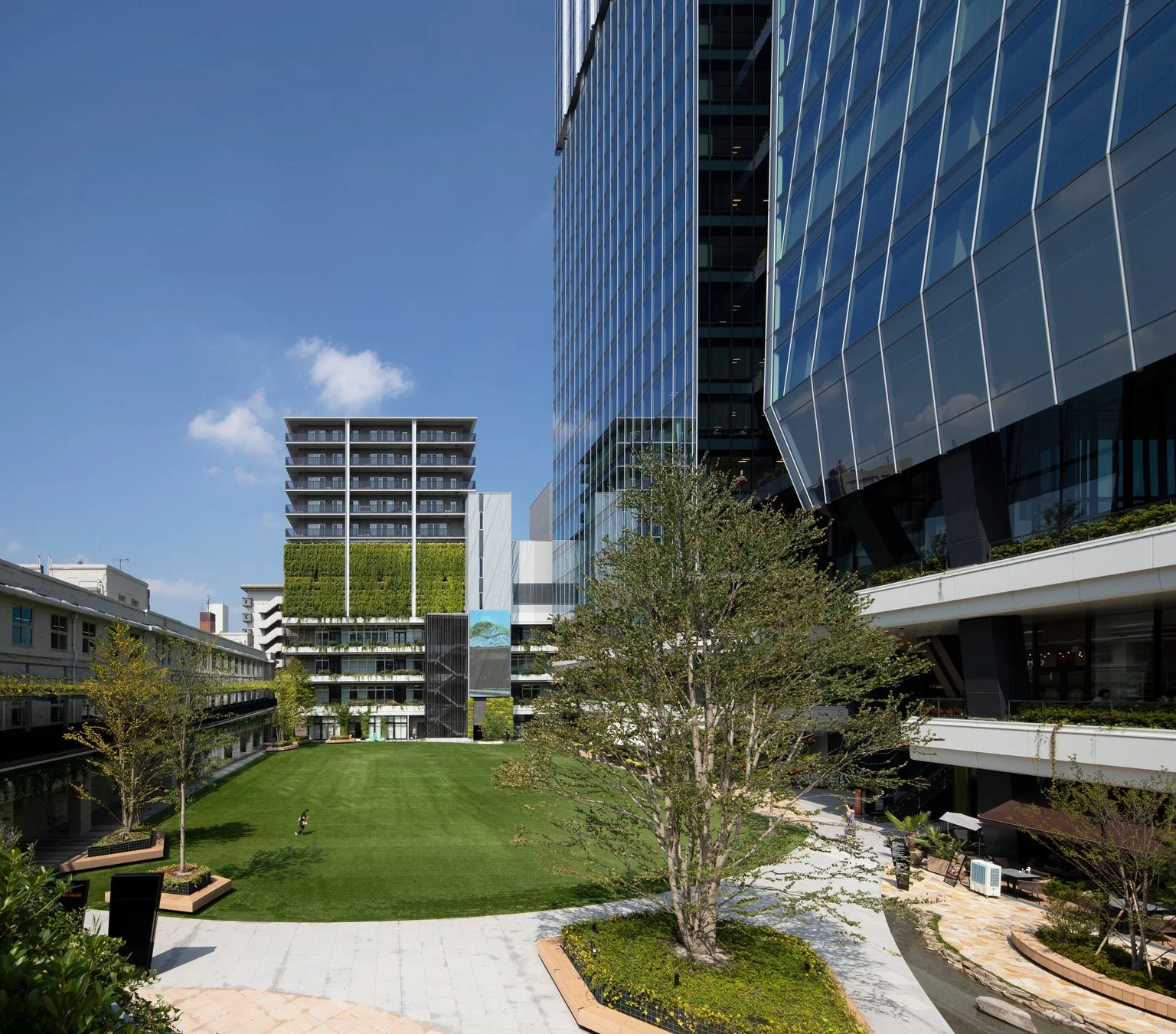 近代的な高層ビル群と緑豊かな広場が広がる都市空間の風景