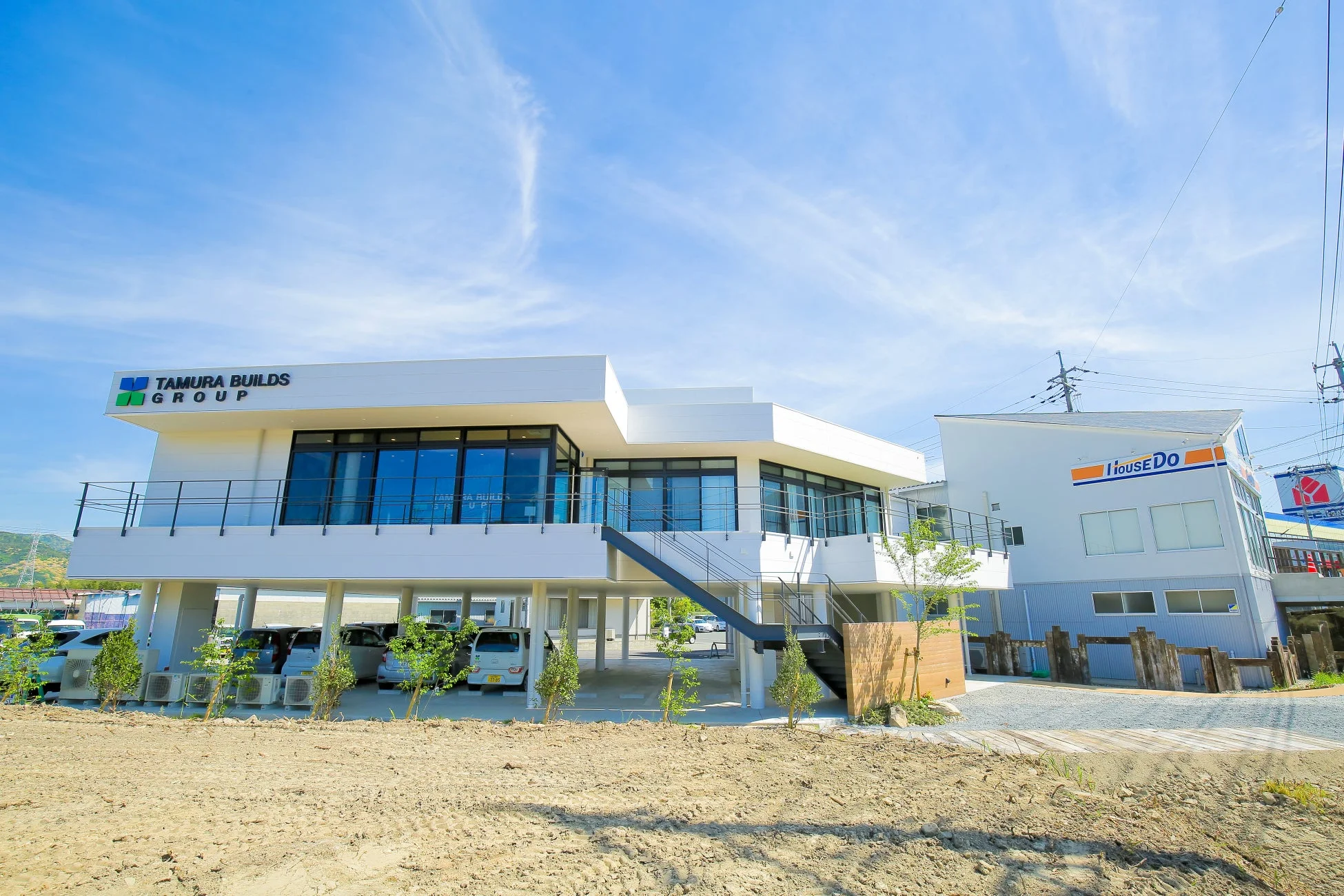 晴れた青空の下に立つTAMURA BUILDS GROUPとiHouseDOの建物