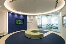 曲線的なデザインが特徴的な、モダンなオフィスエントランスです。青い壁にはテレビと企業ロゴ「oppo」が掲げられ、円形のソファとカーペットが配置されています。奥にはガラス張りのオフィススペースが見えます。