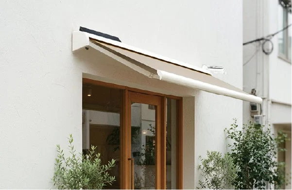 白い外壁の建物に設置されたベージュのオーニング