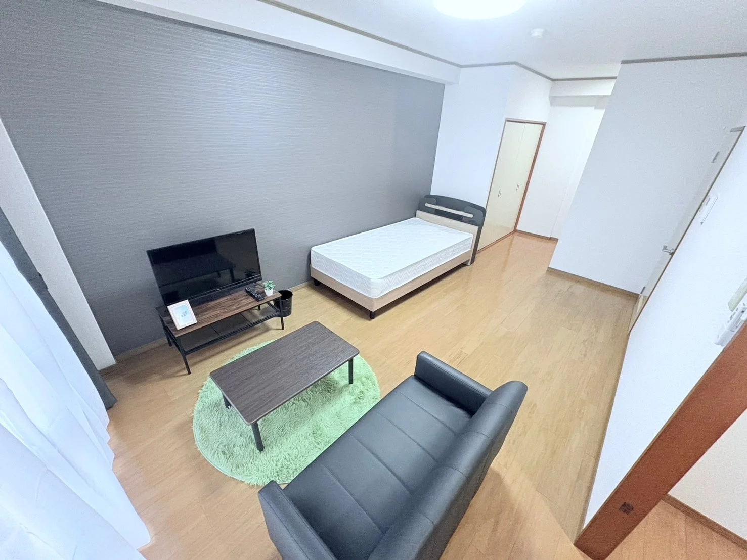 モダンなグレーの壁と木目調のフローリングが特徴のワンルーム