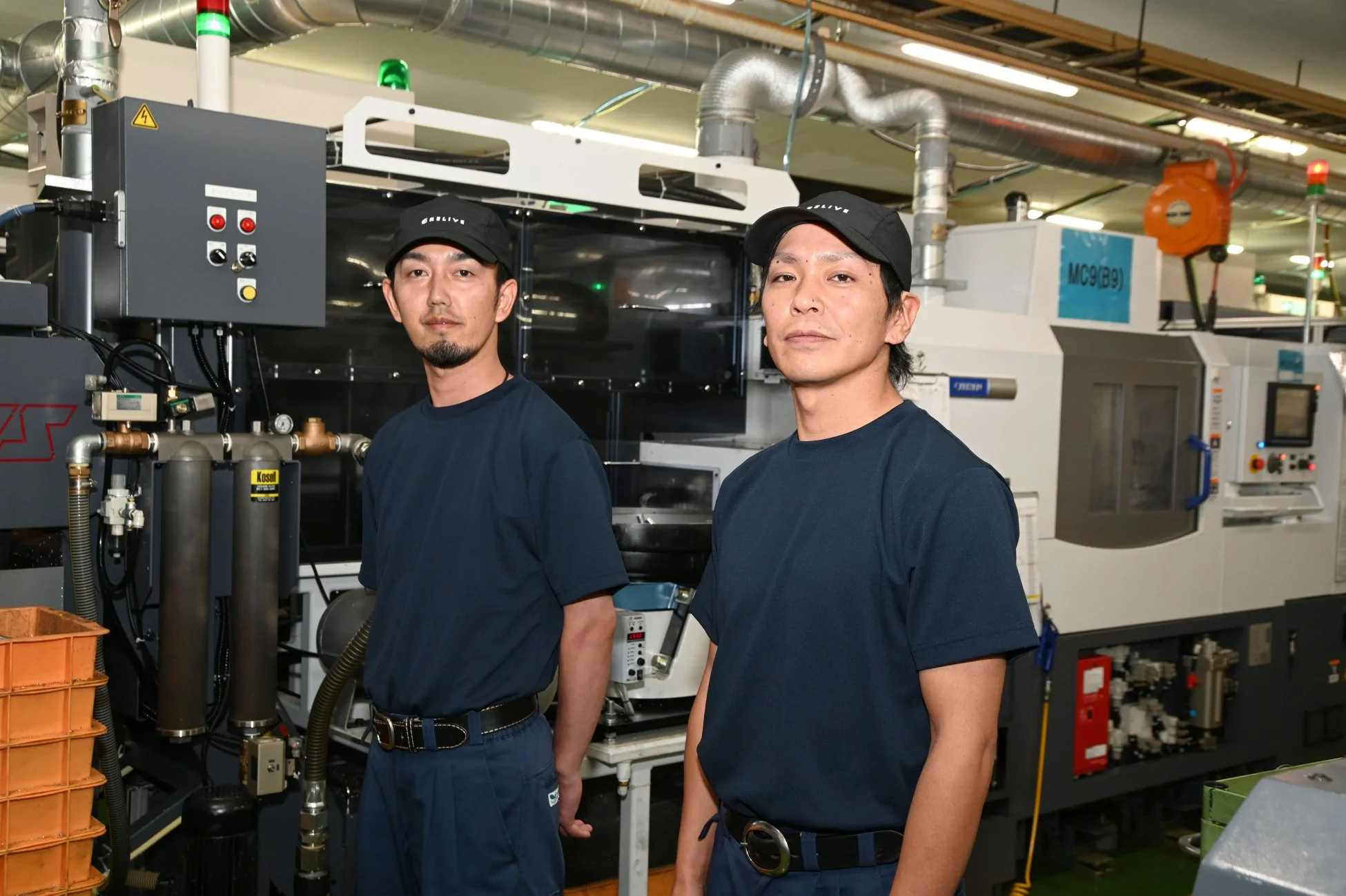 工場内で作業服を着用した2人の男性
