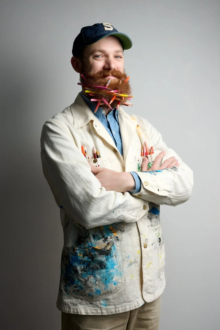 カラフルな鉛筆をひげに差し込んだ男性、エイドリアン・ホーガン氏のポートレート