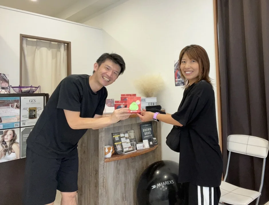 緑色の商品を手に笑顔の男女