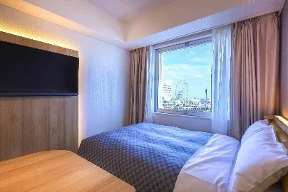 モダンな内装のホテル客室で、大きな窓からは観覧車を含むシティビューが広がっています