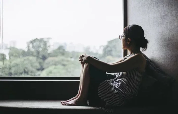窓辺に座り物思いにふける女性