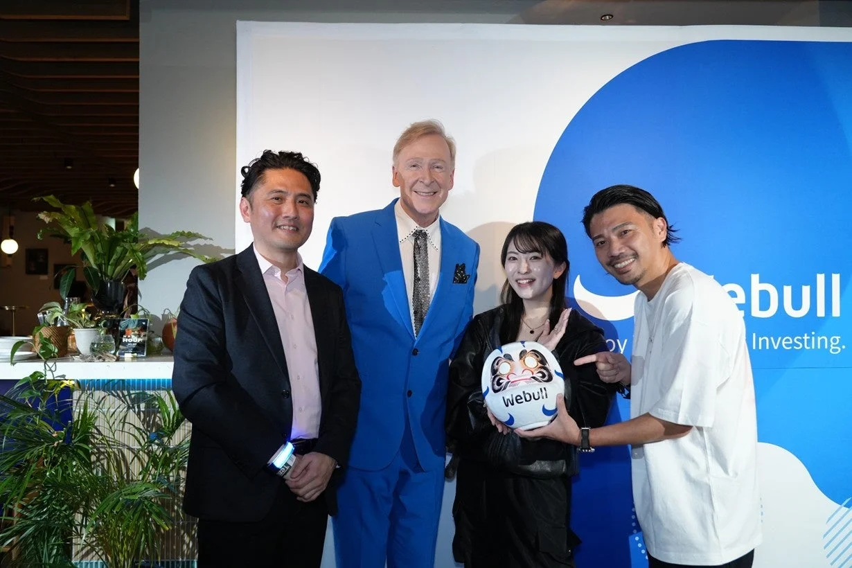 Webullのロゴの前で笑顔で記念撮影をする人々