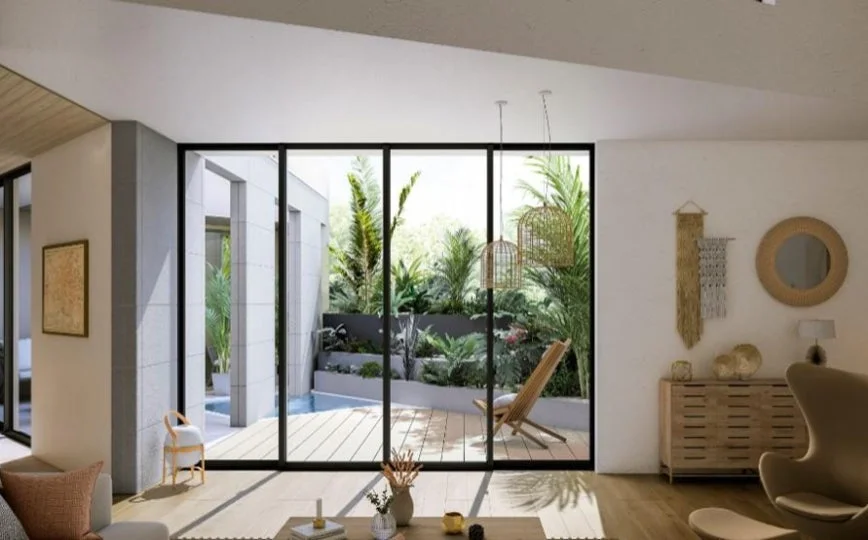 広々としたリビングから、緑豊かな庭とウッドデッキ、小さなプールを望む開放的な空間