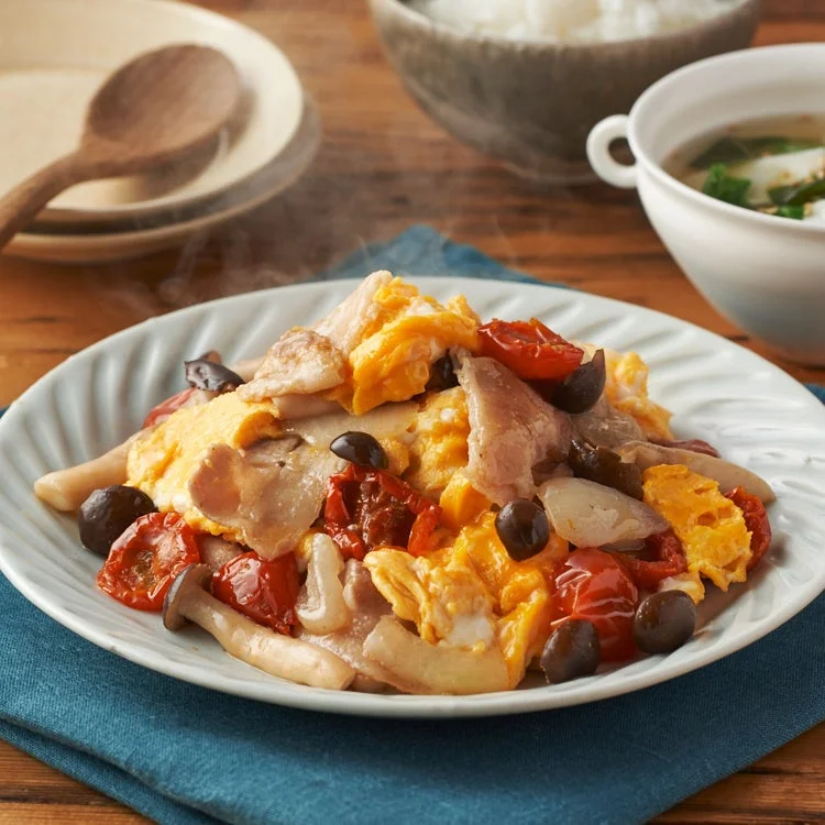 湯気が立ち上るメインディッシュを中心に、ご飯とスープが添えられた食卓の風景