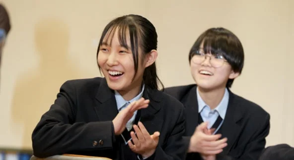 女子生徒が笑顔で拍手している様子