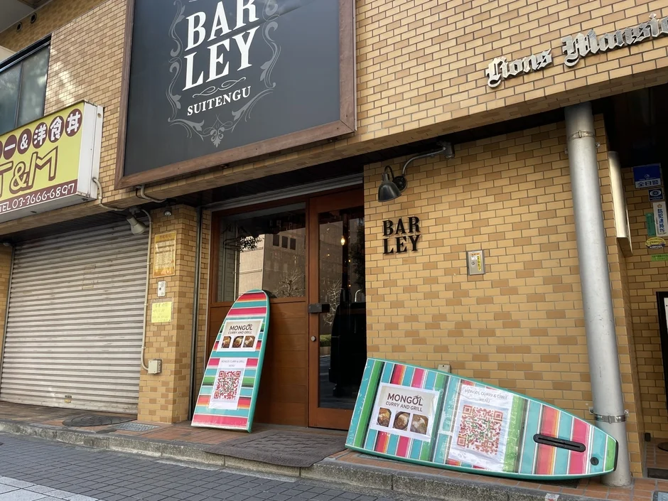 BAR LEY SUITENGUというバーの店舗外観です。隣には「和食&洋食 T&M」があり、店頭には「MONGOL CURRY & GRILL」の看板が置かれています。日本の街角にある商業施設が並ぶ風景です。