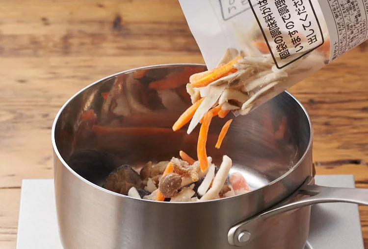 袋に入ったカット済みの野菜が鍋に入れられている調理中の様子