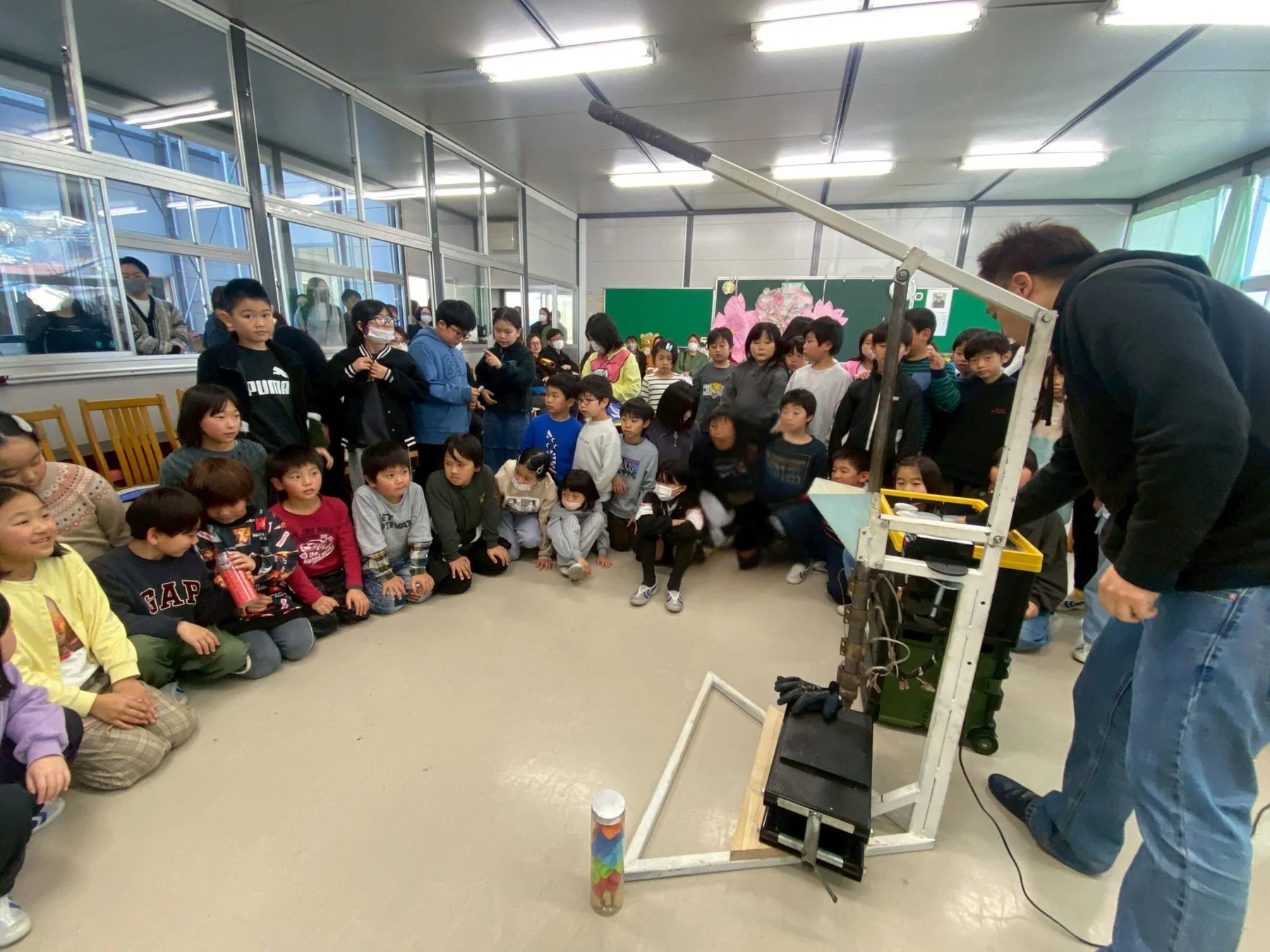 機械のデモンストレーションを見る児童たち