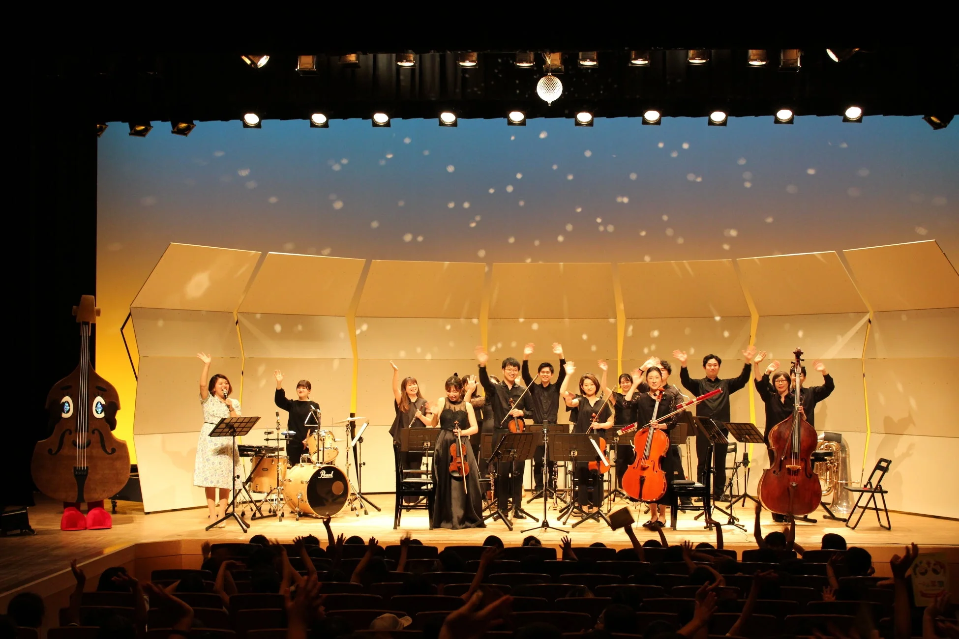 舞台上で観客に手を振るオーケストラ