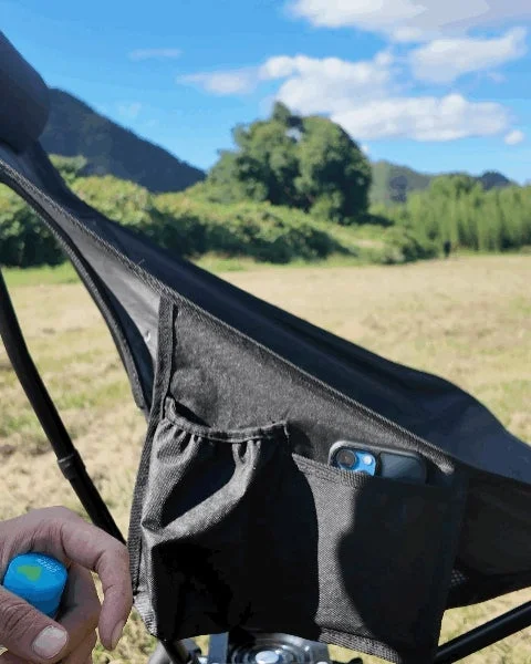 黒いポータブルチェアのサイドポケットにスマートフォンが収納されています