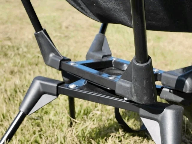 屋外の芝生の上に設置された、黒いフレームとプラスチック製のジョイントで構成されたキャンプチェアの脚部