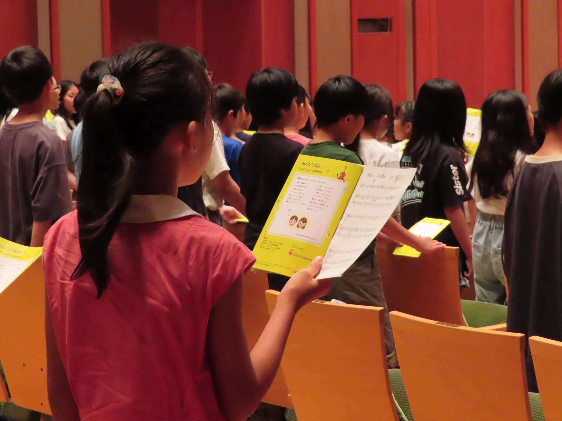 歌集を持つ少女と集まる子どもたち