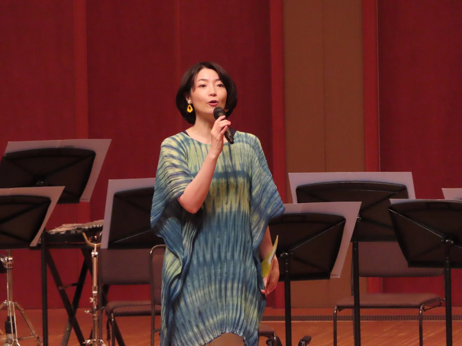 舞台上でマイクを手に話す女性