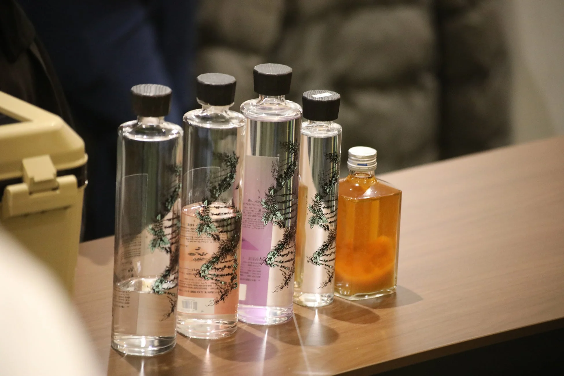 木目調のテーブルに様々な形状のガラスボトルが5本並べられています。