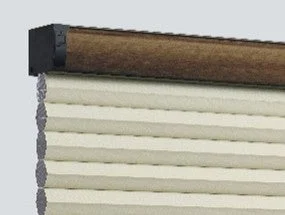 ブラウンのヘッドレールが付いたクリーム色のプリーツブラインドのクローズアップ