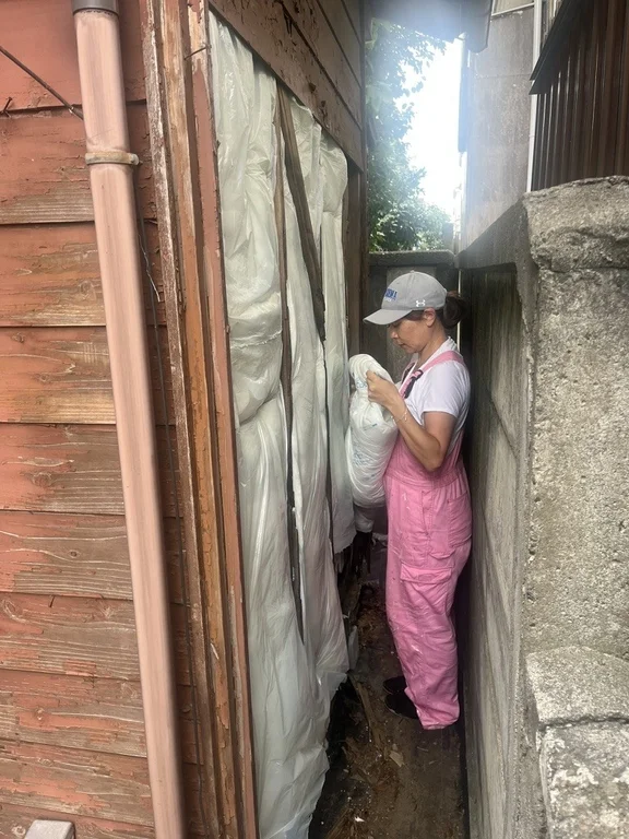 ピンクのオーバーオールを着た女性が建物の間の狭い通路で作業